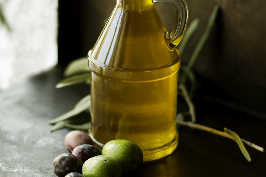 Golden olive oil in a glass cruet with olives